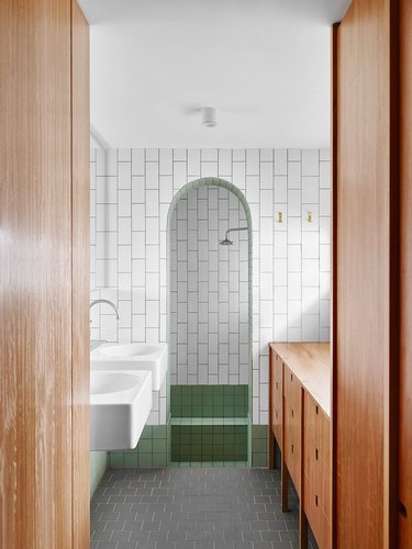 alcove type of shower with white and green tiles