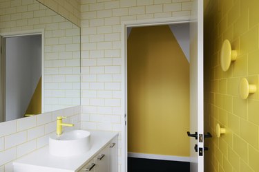 vessel bathroom sink with yellow accent wall and yellow faucet