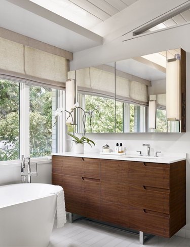 solid surface bathroom countertop with wood vanity and freestanding tub