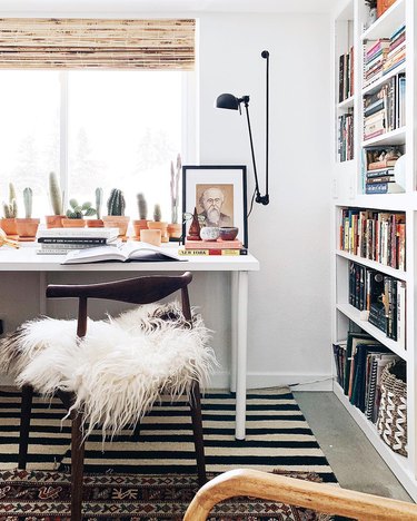 small home office with adjustable wall sconce and floor-to-ceiling bookcase
