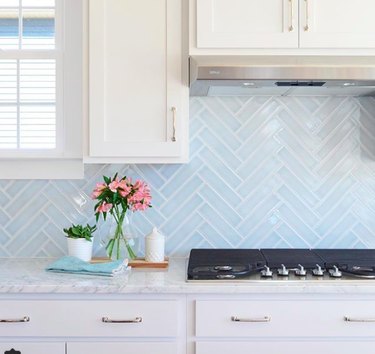 white kitchen with light-blue herringbone tile backsplash