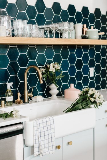 navy hexagon tile backsplash in modern kitchen with open shelving and farmhouse sink