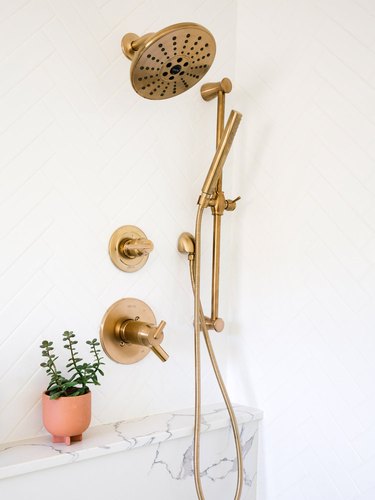 brass bathroom fittings against white walls with marble