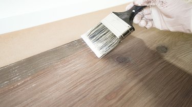 Applying whitewash for faux weathered wood finish.