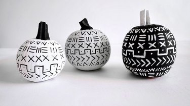 three small pumpkins painted in a black-and-white mud cloth pattern