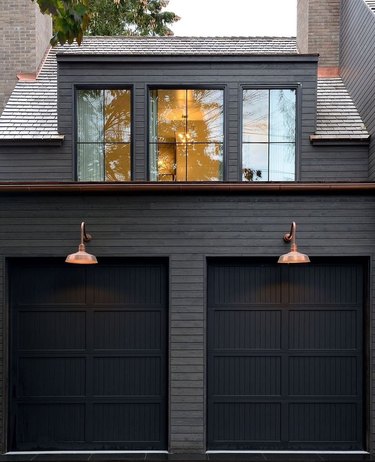 black home exterior with two garage doors and copper wall sconces