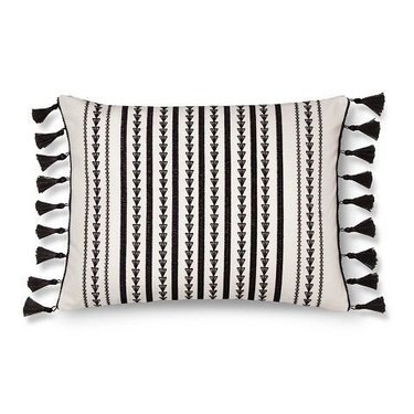 Rectangular black and white throw pillow featuring thin decorated stripes and small black tassels.