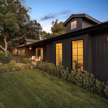 black home exterior with green lawn and steel-framed windows
