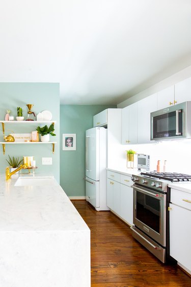 Kitchen with white cabinets, marble island and mine green paint.