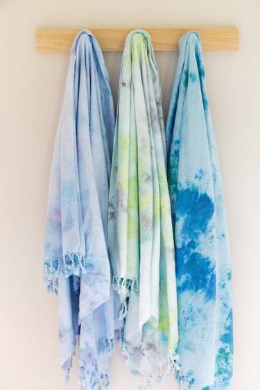 Tie-dyed towels hung on wood rack