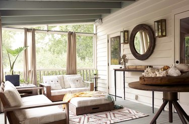 white coastal farmhouse sunroom with wood furniture and patterned rug