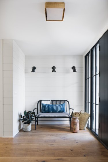 white coastal farmhouse entry with bench and black wall sconces