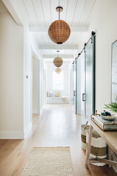 white coastal farmhouse hallway with woven pendant lights and entryway table