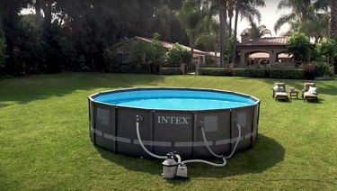 intex above-ground pool in backyard with two lawn chairs and a side table