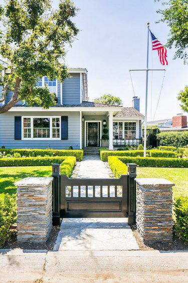 coastal blue home exterior with dark shutters and boxwood hedges