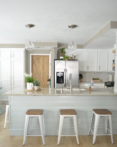 white rustic kitchen with wood barn door and glass pendants over the island