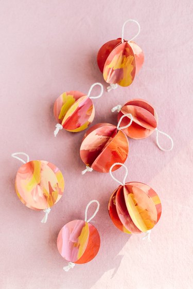 DIY Christmas decorations with colorful ornaments on pink background