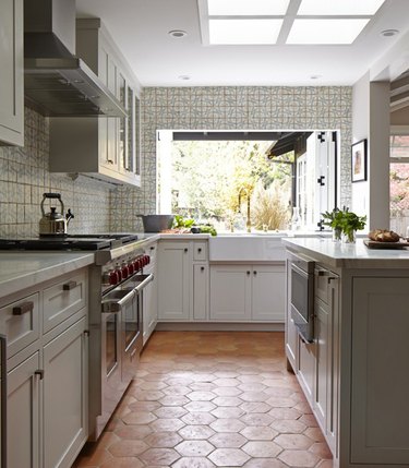 gray cabinets with farmhouse sink and terra cotta kitchen flooring