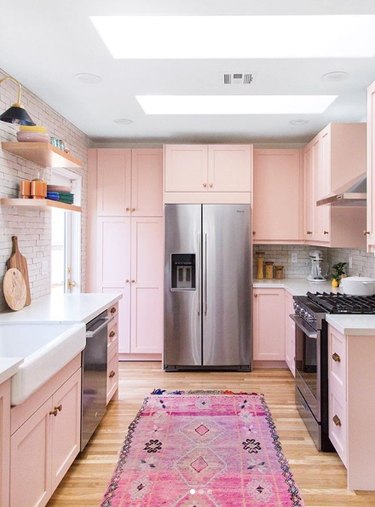 pink kitchen color idea with wood flooring and white subway tile backsplash