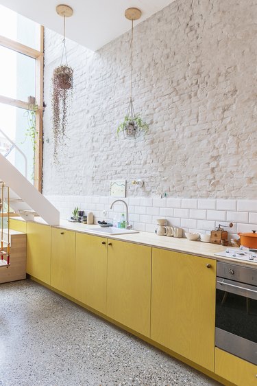 mellow yellow kitchen color trend with white brick wall and subway tile backsplash