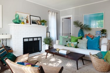 Boho-beach living room with a white brick fireplace, wood furniture, turquoise and green decor, and woven accents.