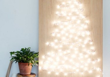 Christmas Tree Themes with White lights installed in plywood in shape of Christmas tree, potted plant.