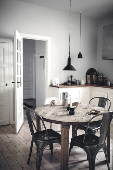 gray and white kitchen with rustic dining table and black pendant lights