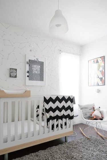 a white celestial-theme nursery with modern rocking chair