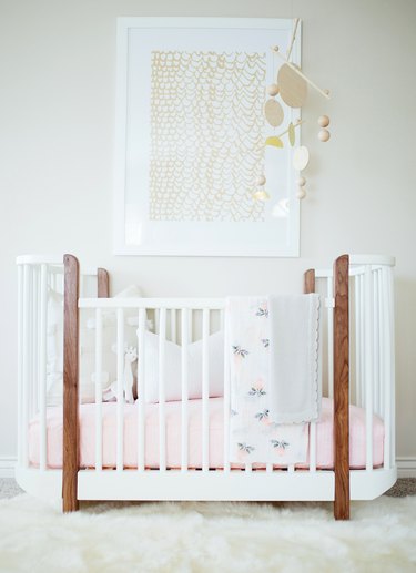 a white boho nursery with crib and decorative mobile