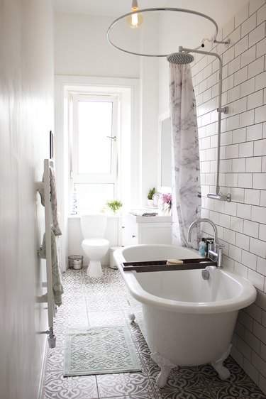 white bathroom with subway tile accent wall and clawfoot bathtub