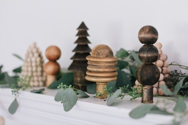 Fireplace mantle decorated with wooden trees and eucalyptus cuttings