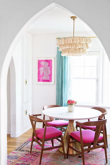 fuchsia pink dining room with aqua curtains and a tassel chandelier