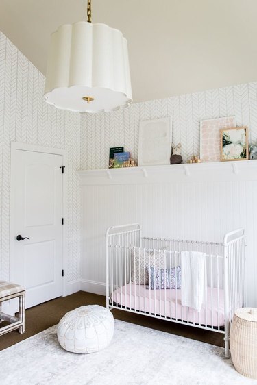 a white nursery with white crib and pendant light