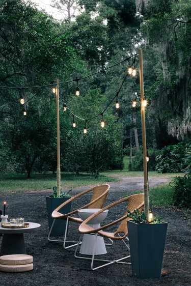 String lights on poles inside planters; two mid-century modern lawn chairs