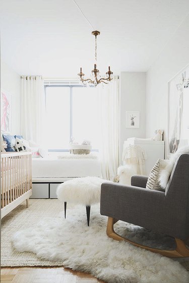 white nursery with gold candelabra chandelier and sheepskin rug