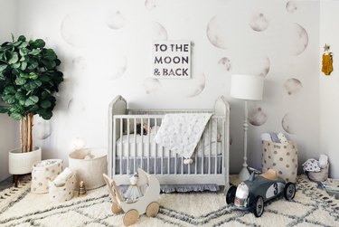 moon wallpaper mural in a white nursery with gray crib