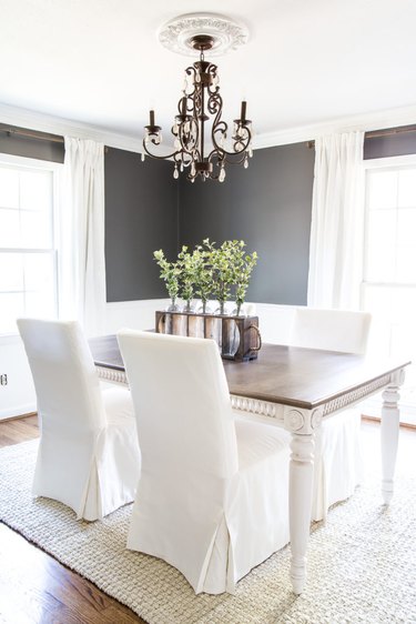 gray dining room with white wainscoting and slipcovered chairs