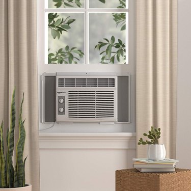 air conditioning unit on window near plant and books