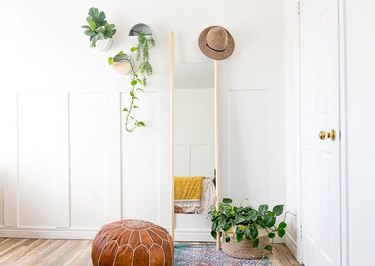 Mirror with dowels in bohemian bedroom with plants.