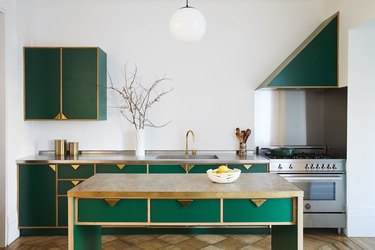 modern kitchen island with green cabinets and brass pulls