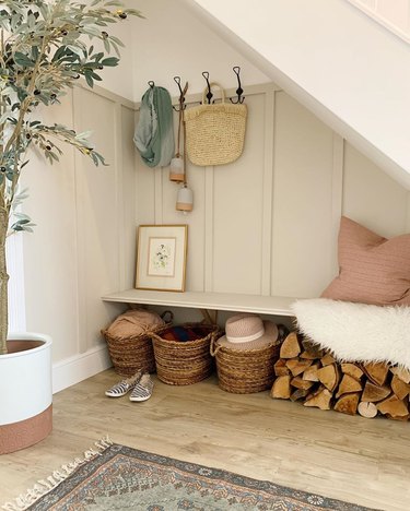 Under the stairs storage in small mudroom with baskets and seating