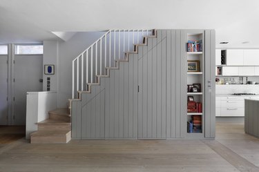Under the stairs storage with gray paneling and seamless doors
