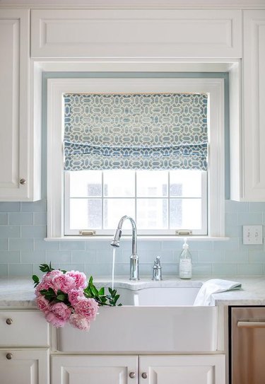 glass subway tile kitchen backsplash with white cabinets and farmhouse sink