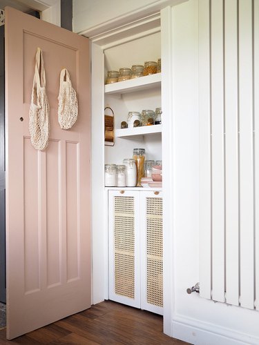 Under the stairs storage pantry with pink door and cane cabinets