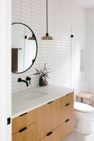 white subway tile in bathroom with minimalist bathroom storage and black faucet