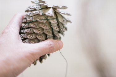 Twisting floral wire around pinecone