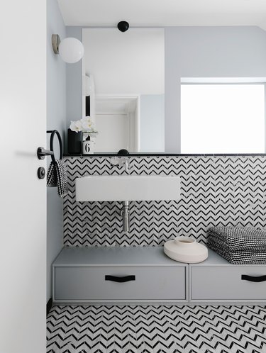 Scandinavian bathroom with black and white patterned tile and wall mounted sink