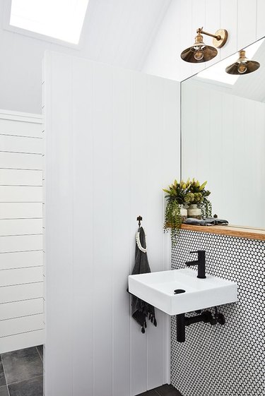 Scandinavian bathroom with white penny tile mosaic and black grout