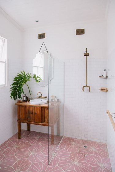 white bathroom with pink patterned floor tiles and wooden vanity