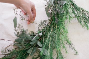 Tucking sprig of eucalyptus into wreath